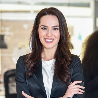 Businesswoman leader looking at camera in modern office with multi-ethnic businesspeople working at the background. Teamwork concept. Caucasian woman.