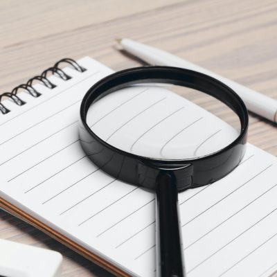 Magnifying glass and notebook on wooden table